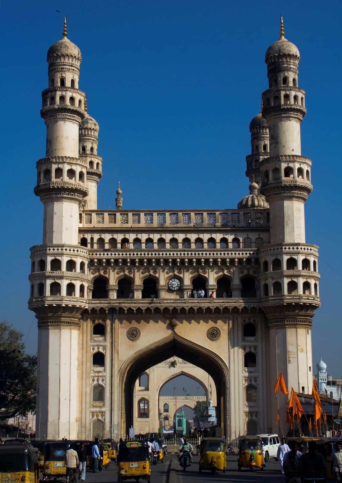 The Charminar in Hyderabad against a deep blue sky, autorickshaws at its foot