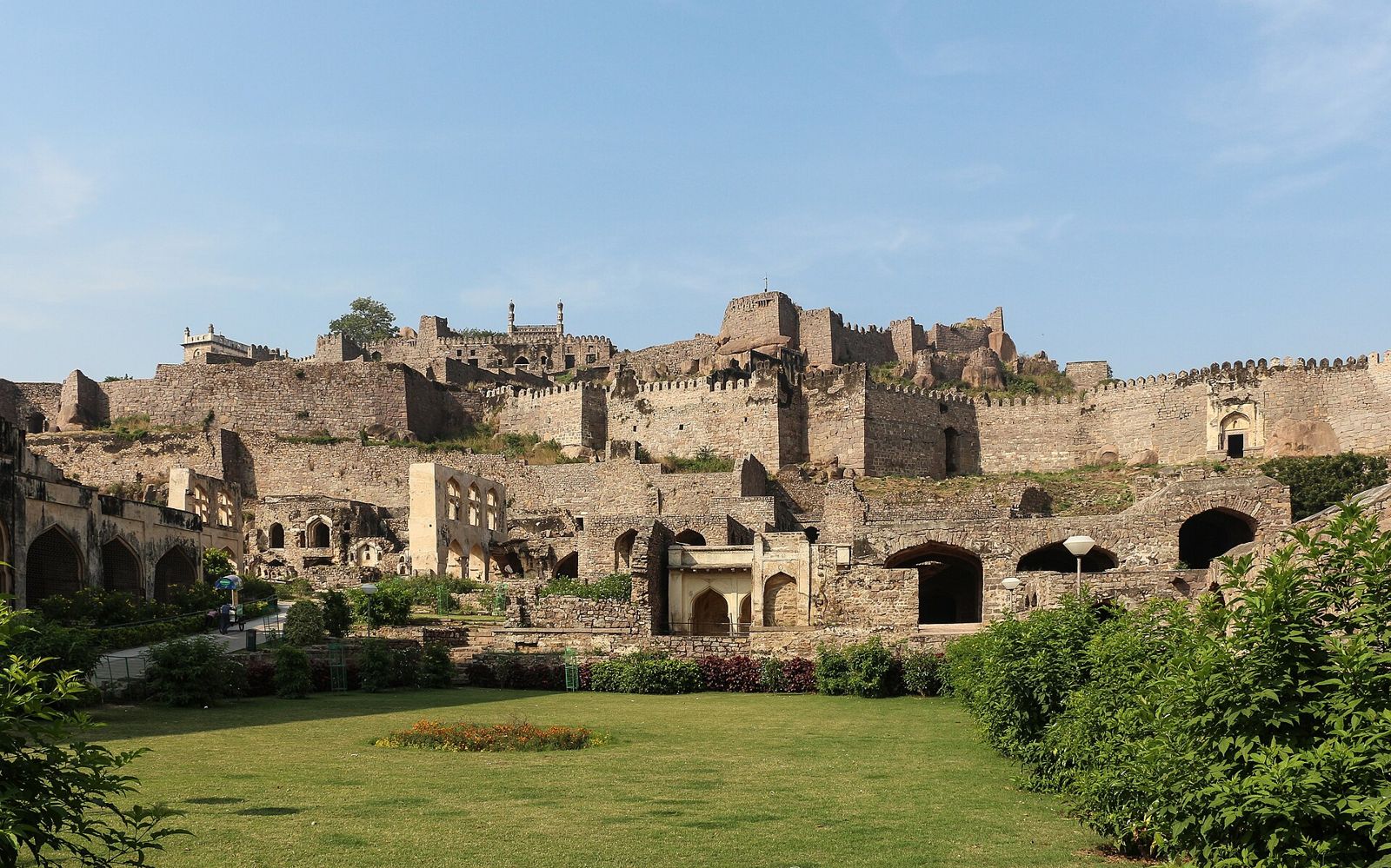 The walls and terraces of Golconda Fort above a green lawn