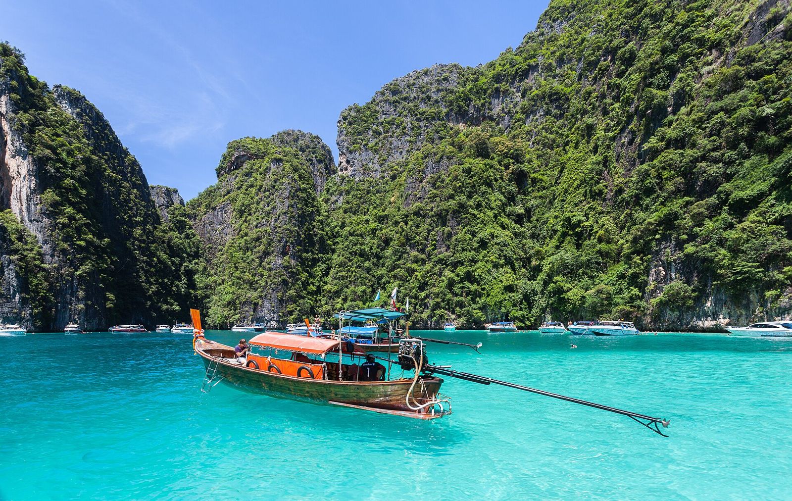 A long-tail boat on turquoise water under the cliffs of Phi Phi in Thailand